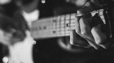 grayscale photo of person playing guitar