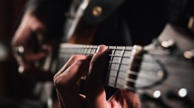 man playing guitar in close up photography
